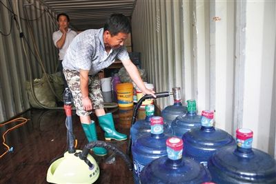 5月21日，朝阳区龙爪树村一家“黑水厂”，工人在集装箱内灌装假桶装水。